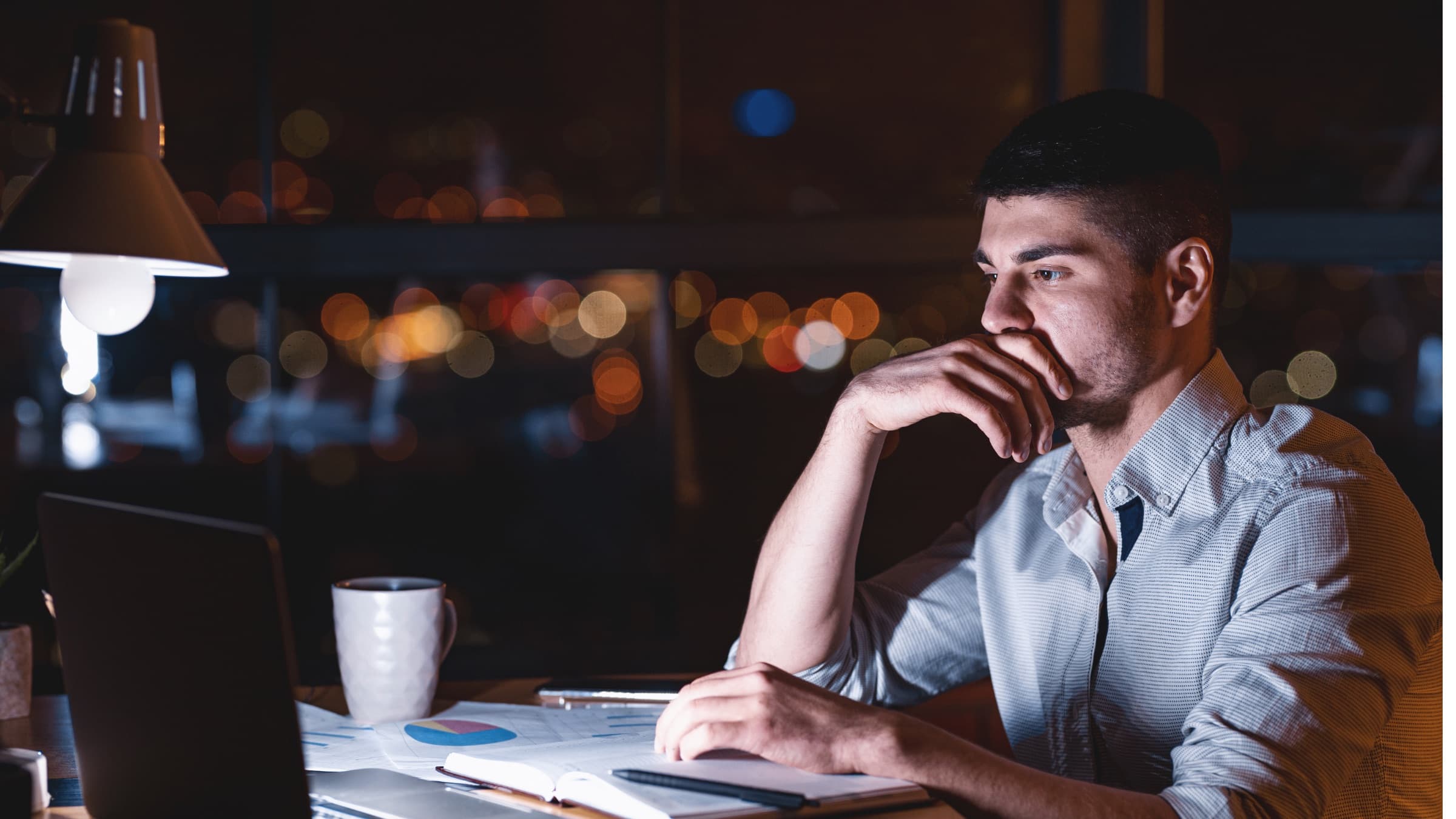 A founder working late at a desk overlooking city lights